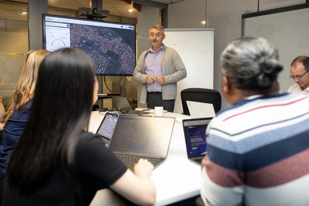 A man presenting to a small group of colleagues in an office meeting room.