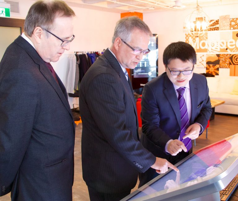 Ed Wei (right), Director of Engineering at MappedIn, demonstrates the company’s technology to Gary Goodyear, Minister of State for FedDev Ontario (centre), and Stephen Woodworth, MP for Kitchener Centre. (Communitech photo: Anthony Reinhart)