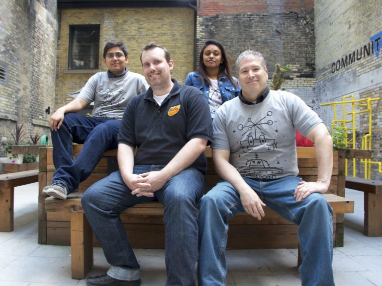 Wagepoint team sitting on a wooden bench and planter