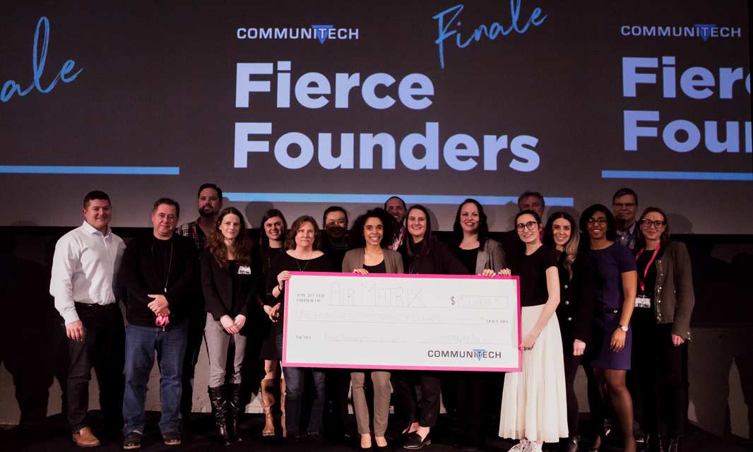 A group of people standing onstage at Fierce Founders with a giant cheque